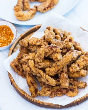 Breaded deep fried pork pieces are a golden brown color, sitting on a white plate.