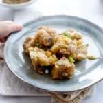 Crunchy fried golden brown bite-sized rib pieces sit on a grey clay plate.