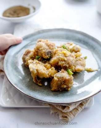 Crunchy fried golden brown bite-sized rib pieces sit on a grey clay plate.