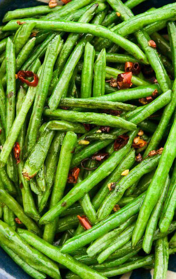 Bright green long beans are fried with sliced chilis.